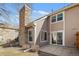 Exterior view of a tan home, including a patio and stone chimney at 1929 S Xanadu Way, Aurora, CO 80014