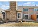 Tan home with a stone chimney, backyard patio, and sliding glass door at 1929 S Xanadu Way, Aurora, CO 80014