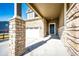 Close-up of stone-accented home exterior featuring a covered porch, front door, and attached garage at 469 S Olathe St, Aurora, CO 80017