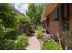 Landscaped walkway between brick buildings shows lush greenery and flowering plants leading to a shaded outdoor space at 400 S Steele St # 64, Denver, CO 80209