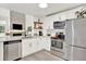 This modern kitchen features stainless steel appliances and sleek white cabinetry and view to the living room at 3030 W Prentice Ave # D, Littleton, CO 80123