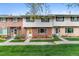 Townhome exterior has brick accents, mature landscaping and green lawn at 12708 W Virginia Ave, Lakewood, CO 80228