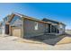 Gray home with garage, concrete patio, and desert landscaping at 2263 Serenidad St, Brighton, CO 80601