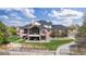 Expansive brick home with a deck, lush lawn, mature trees, and a driveway winding through a gated entrance at 3 White Pelican Cir, Thornton, CO 80241