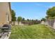 Large, fenced backyard with a well-kept lawn, mature trees, and a gas grill at 6260 E 114Th Ave, Thornton, CO 80233