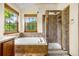 Tiled bathroom with soaking tub and separate shower with natural light from two windows at 473 Somerset Dr, Golden, CO 80401