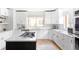 This kitchen boasts white cabinets and countertops, a gas cooktop island, stainless appliances, and light wood flooring at 1272 S Milwaukee St, Denver, CO 80210