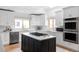 Bright kitchen features white cabinets, stainless appliances, an island with cooktop, and light wood flooring at 1272 S Milwaukee St, Denver, CO 80210