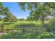 Expansive backyard featuring lush grassy fields, mature trees, and a charming wooden fence and gate at 20596 E Shefield Ct, Parker, CO 80138