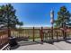 The sunny deck has high stools with seating, an umbrella for shade, and a green grassy view beyond at 7605 Shenandoah Dr, Elizabeth, CO 80107