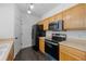 Efficient kitchen with wood cabinets, black appliances, and ample counter space at 5255 Memphis St # 1112, Denver, CO 80239