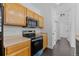 Well-lit kitchen with wood cabinetry, black appliances, and dark hardwood floors at 5255 Memphis St # 1112, Denver, CO 80239