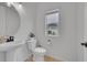 Well-lit half bathroom featuring a pedestal sink, toilet, and window, all in a minimalist design at 4612 S Wenatchee St # A, Aurora, CO 80015