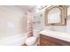 Clean bathroom with a shower-tub combination, glass shelves, and a decorative mirror above a stylish vanity at 8300 W 87Th Dr # B, Arvada, CO 80005