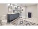 Well-lit bathroom featuring double sink vanity, decorative mirrors, and glass-enclosed shower at 1063 Sandstone Cir, Erie, CO 80516