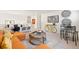 Open living room features an orange sofa, ottomans, a table and chairs, and workspace in the background at 3347 Belleville Ridge Rd, Elizabeth, CO 80107