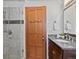 Modern bathroom with a glass-enclosed shower, granite vanity, and decorative wood door at 2535 Leyden St, Denver, CO 80207