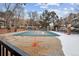 Community pool covered with a safety tarp surrounded by trees and snow patches at 2003 S Helena St # D, Aurora, CO 80013
