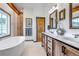 Bathroom with wood cabinets, double sink, and a soaking tub at 8191 S Homesteader Dr, Morrison, CO 80465