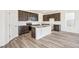 Bright kitchen features stainless appliances, dark cabinetry, a spacious island with granite countertops and hardwood flooring at 13432 E 110Th Way, Commerce City, CO 80022