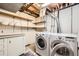 Laundry room with front load washer and dryer, open shelving, and utility sink at 2556 S Eagle Cir, Aurora, CO 80014
