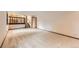 Open living area with neutral carpet leading to a staircase and a doorway at 2556 S Eagle Cir, Aurora, CO 80014
