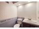 Cozy half-bathroom with patterned wallpaper, white fixtures, and tiled countertop at 2556 S Eagle Cir, Aurora, CO 80014