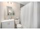 Well-lit bathroom featuring a modern vanity, mirror, and shower with a white curtain at 8299 E Kenyon Ave, Denver, CO 80237