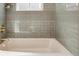 Close-up of the bathroom tub with elegant tile work, brass fixtures, and a window for natural light at 10121 W 70Th Dr, Arvada, CO 80004