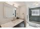Stylish bathroom featuring a marble countertop vanity, modern fixtures, and a tub-shower with blue tile at 10121 W 70Th Dr, Arvada, CO 80004