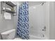 Well-lit bathroom features a bathtub with blue floral shower curtain and metal shelving at 837 E 98Th Ave # 405, Thornton, CO 80229