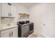 Well-organized laundry room features a utility sink, white cabinets, and modern washer and dryer at 1832 Marlowe Cir, Erie, CO 80516
