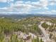 An aerial view showing a house surrounded by trees, mountains in the background, and a curving road at 800 Highway 72, Golden, CO 80403