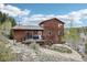 A wooden two-story home featuring a deck and sliding glass door on a hillside at 800 Highway 72, Golden, CO 80403