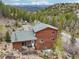 Scenic view of a two-story home boasting a deck and a backdrop of snow-capped mountains and lush forest at 800 Highway 72, Golden, CO 80403