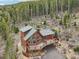 Exterior view of a two-story home nestled in the trees featuring wood siding and a large deck with chairs at 800 Highway 72, Golden, CO 80403