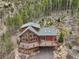 A wooden home on a hillside features a large deck with chairs and beautiful forest surroundings at 800 Highway 72, Golden, CO 80403