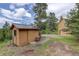 Exterior view of the wooden shed and portion of the house with a nice landscape at 31150 Manitoba Dr, Evergreen, CO 80439