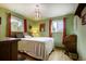 Bedroom with green walls, wood floors, two windows, and a cozy bed with throw pillows at 10373 W 75Th Ave, Arvada, CO 80005