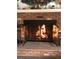 A brick fireplace with protective glass doors showcases burning wood inside and decorative items on the mantle at 10373 W 75Th Ave, Arvada, CO 80005
