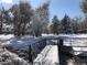 Snowy neighborhood scene featuring mature trees and a quaint pedestrian bridge on a clear winter day at 10373 W 75Th Ave, Arvada, CO 80005
