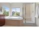 Bright bathroom with a soaking tub, glass shower, tile flooring, and large windows for natural light at 1513 Cannon Mountain Dr, Longmont, CO 80503