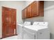 Convenient laundry room featuring white washer and dryer and wooden cabinets at 1513 Cannon Mountain Dr, Longmont, CO 80503