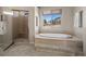 Spa bathroom featuring large window, soaking tub, walk-in shower with glass doors, and neutral finishes at 20217 Kenneth Lainer Dr, Monument, CO 80132