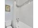 Clean bathroom featuring a bathtub with a shower, a toilet, and white tiled walls with decorative accent tiles at 6721 S Clayton Way, Centennial, CO 80122