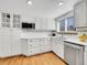 Well-lit kitchen with white cabinets, stainless steel appliances, and hardwood floors at 6721 S Clayton Way, Centennial, CO 80122