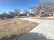 View of a street with well-maintained lawns, trees, sidewalks, and a modern concrete driveway at 1120 Tucson St, Aurora, CO 80011