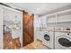 Convenient laundry room with a stylish barn door, modern washer/dryer, and ample counter space at 2357 Oak Ridge Rd, Sedalia, CO 80135