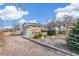 Exterior of a brick home with a gravel driveway, landscaping, and mature trees at 3700 Miller St, Wheat Ridge, CO 80033