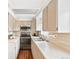 Galley kitchen featuring tile countertops, stainless steel appliances, and wood-look flooring at 3700 Miller St, Wheat Ridge, CO 80033